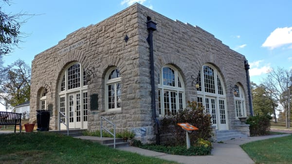 The 1928 stone shelter with tall arched windows that encloses the Adair cabin in Osawatomie.