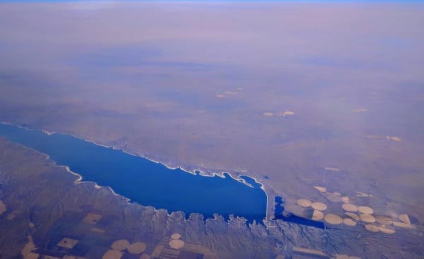 Lake McConaughy seen from the air, its white sand shoreline running to Kingsley Dam beside circles of irrigated fields.