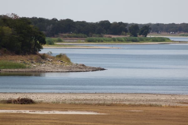 Low water exposing a sandy shoreline at Lake Somerville during the 2011 drought, with wooded shores beyond.