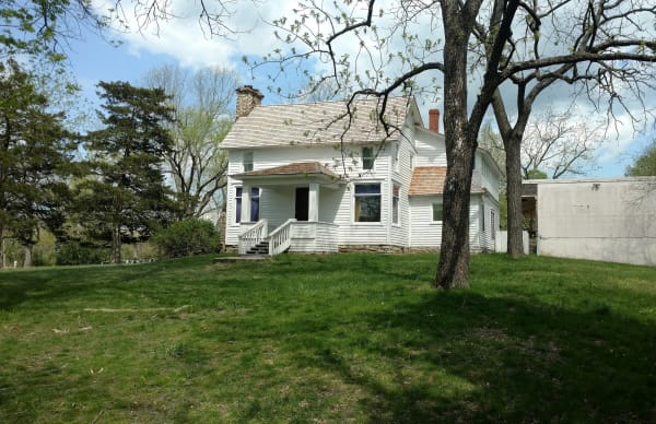 The white Rocky Ridge farmhouse of Laura Ingalls Wilder under spring trees near Mansfield.