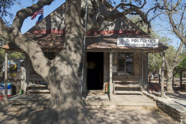 The weathered wooden store and post office at Luckenbach under the spreading limbs of a large oak.