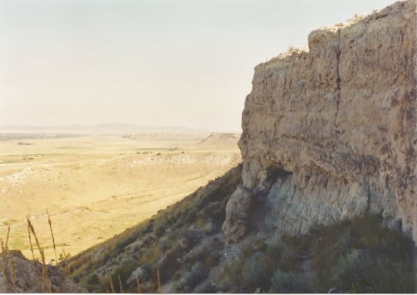 The pale limestone cliff of the Madison Buffalo Jump falling away to dry grassland that stretches toward the horizon