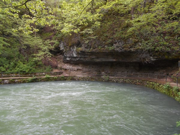 The blue-green pool of Maramec Spring below a mossy limestone bluff.