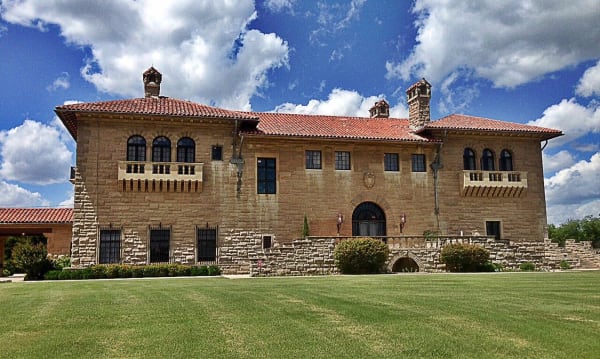 The stone south front of the Marland Mansion in Ponca City under a red tile roof.