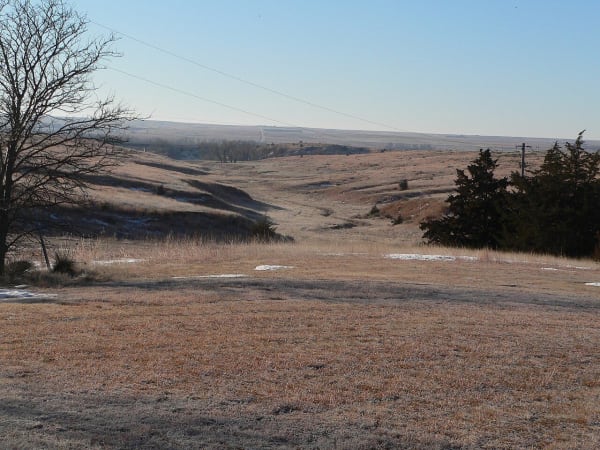 Winter grassland falls away southwest from the Massacre Canyon monument into the canyon toward the Republican valley.