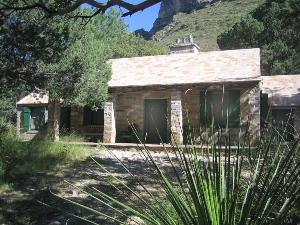 The stone Pratt Cabin with its pale roof among trees and yucca at the mouth of McKittrick Canyon.
