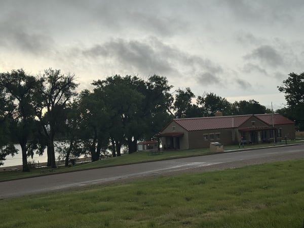 The Meade State Park office under tall trees beside the park road on a cloudy day.