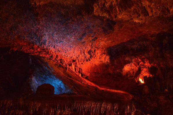 Cave formations in Meramec Caverns lit in red and blue along a tour passage.