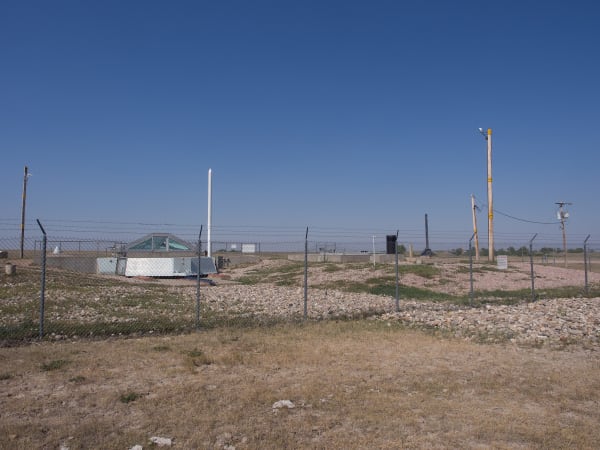The fenced Delta-09 missile silo site, a gravel pad with antennas and the glass-covered silo door, on the open prairie