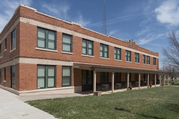 The two-story red brick Mobley Hotel in Cisco, with green-framed windows and a long covered porch lined with benches along one side.