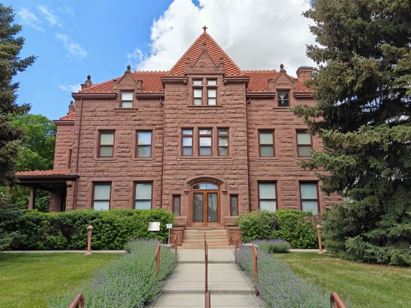The Moss Mansion in Billings, red sandstone with a steep gable and arched entry, a lavender-lined walk leading to the door