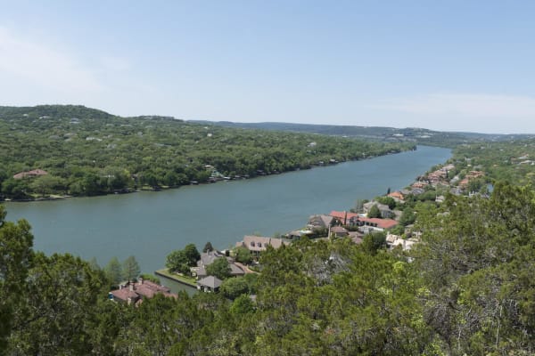 Lake Austin winding between wooded hills and waterfront houses, seen from the top of Mount Bonnell.