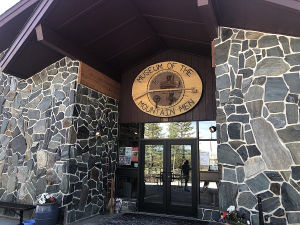 The stone-walled entrance of the Museum of the Mountain Man in Pinedale, an oval wooden sign over the glass doors