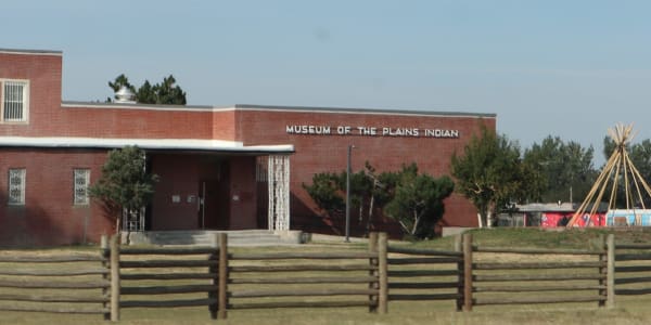 The low red-brick Museum of the Plains Indian in Browning behind a split-rail fence, its name across the front