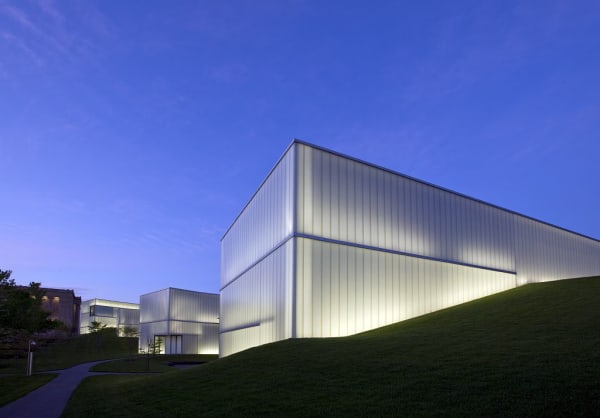 The translucent glass boxes of the Bloch Building at the Nelson-Atkins, glowing at dusk above a grassy slope.