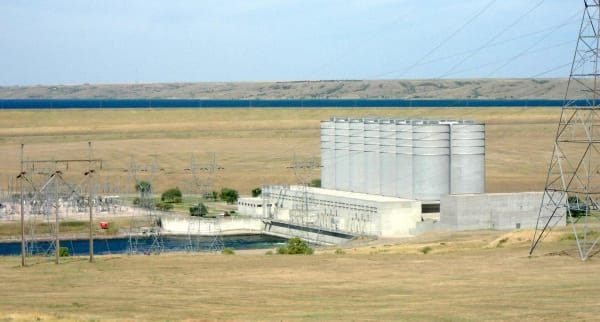 The Oahe powerhouse below the dam, with its row of tall cylindrical surge tanks and transmission towers beside the tailrace