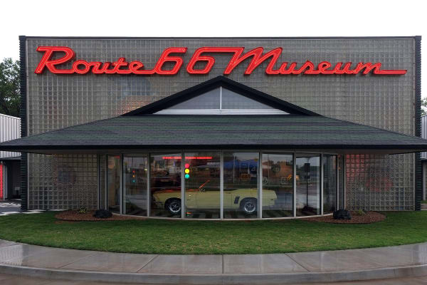 The glass-fronted Oklahoma Route 66 Museum in Clinton under its red script sign.