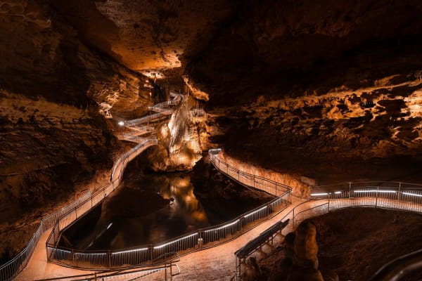 A lighted walkway winding past stalagmites and flowstone in a large chamber of Onondaga Cave.