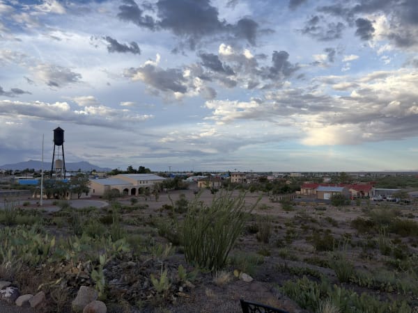 The village of Columbus and its water tower seen from the hill at Pancho Villa State Park under a cloudy evening sky