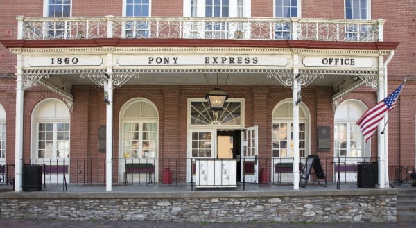 The Patee House porch with white iron columns and a sign reading 1860 Pony Express Office in St. Joseph.
