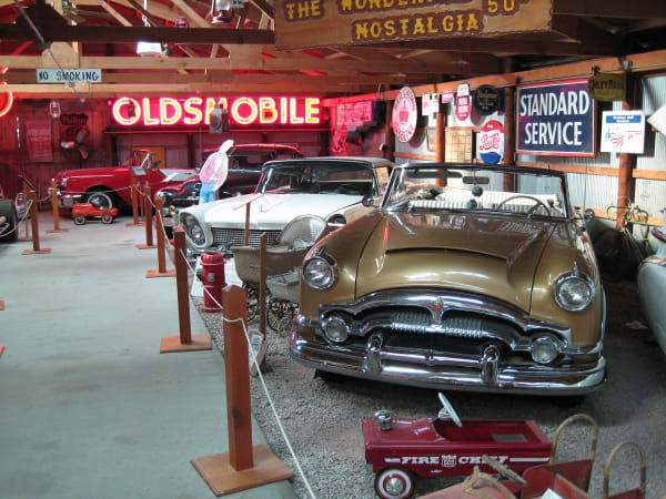 Mid-century cars and old neon and enamel signs crowded inside a building at the Pioneer Auto Show in Murdo