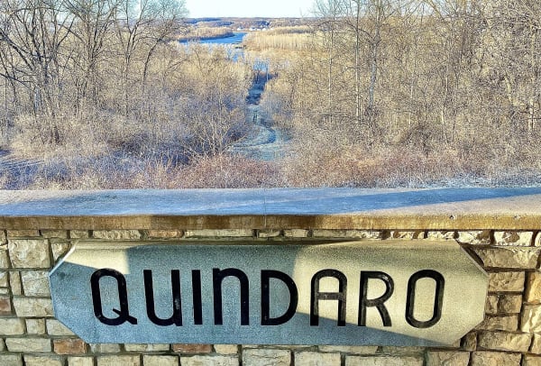 A stone wall lettered Quindaro at the overlook, above a frosted wooded ravine running down toward the Missouri River.