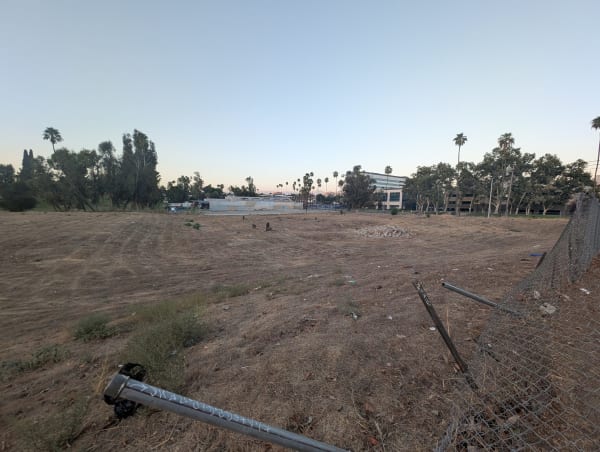 The empty fenced lot in the Tequesquite Arroyo where Riverside's second Chinatown stood, a fallen fence post in the foreground.