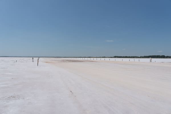 The flat white salt plain of the selenite digging area under a blue sky.