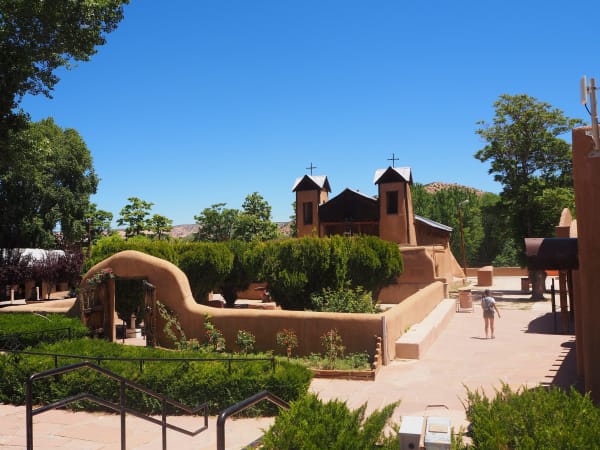 El Santuario de Chimayó, its twin bell towers rising behind an adobe-walled courtyard
