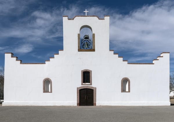 The whitewashed stepped facade and bell niche of the Socorro Mission church in Socorro, near El Paso.