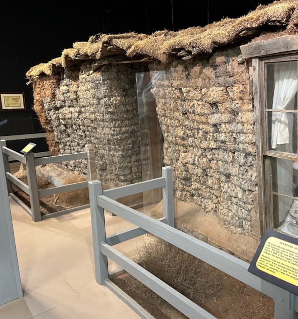 The stacked-sod walls and window of the 1894 sod house, preserved inside the museum shelter.