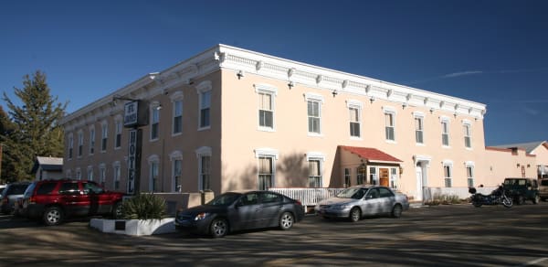 The long two-story front of the St. James Hotel in Cimarron, cars parked outside