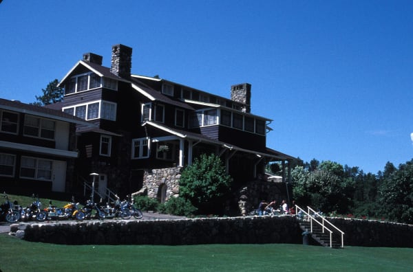 The dark-shingled State Game Lodge with its stone chimneys and front lawn in Custer State Park