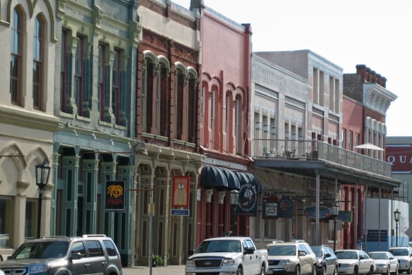 A row of nineteenth-century commercial buildings with ornate brick and iron fronts and balconies on the Strand in Galveston.