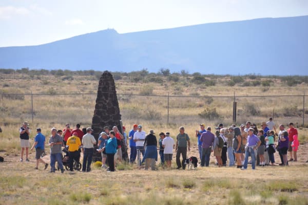 Visitors gathered around the dark stone obelisk marking ground zero during a Trinity Site open house