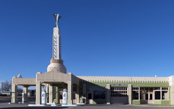 The Art Deco Tower Station and U-Drop Inn in Shamrock, its tiled spire rising above the gas pumps under a clear blue sky.