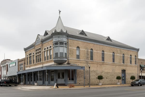 The two-story brick Grand Opera House in Uvalde, with a corner turret, a bay window and arched upper windows.