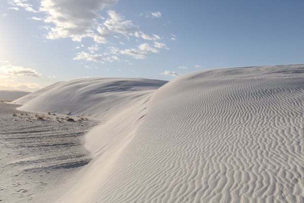 A rippled crest of white gypsum sand curving across the dunes at White Sands under a lightly clouded sky