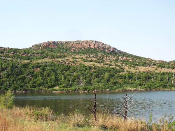 A granite-topped mountain rising above a lake in the Wichita Mountains Wildlife Refuge.
