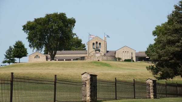 The low limestone Will Rogers Memorial Museum on its Claremore hilltop behind an iron fence.