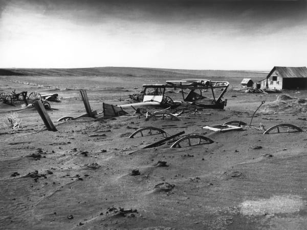 Farm machinery half buried by drifted soil in a barn lot at Dallas, Gregory County, during the Dust Bowl in 1936