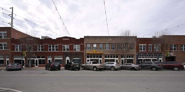 A row of two-story brick storefronts on North Greenwood Avenue in Tulsa, with cars parked along the street.
