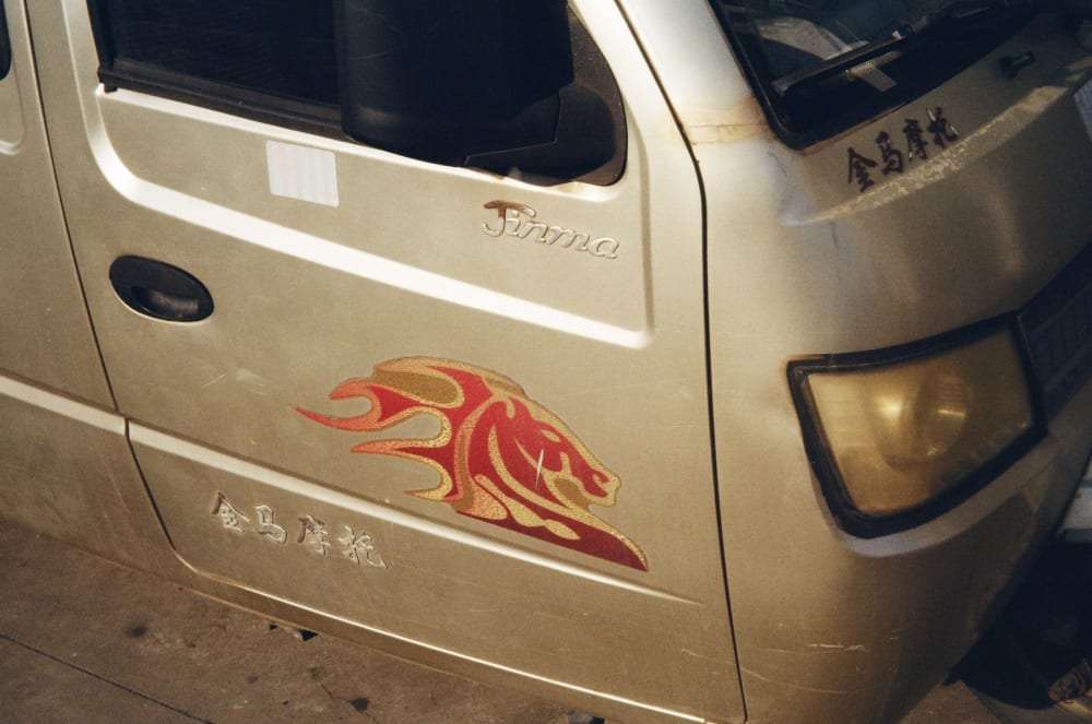 A golden truck with a red horse decal