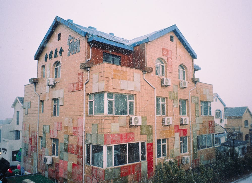 Snow falling around a peach-colored building