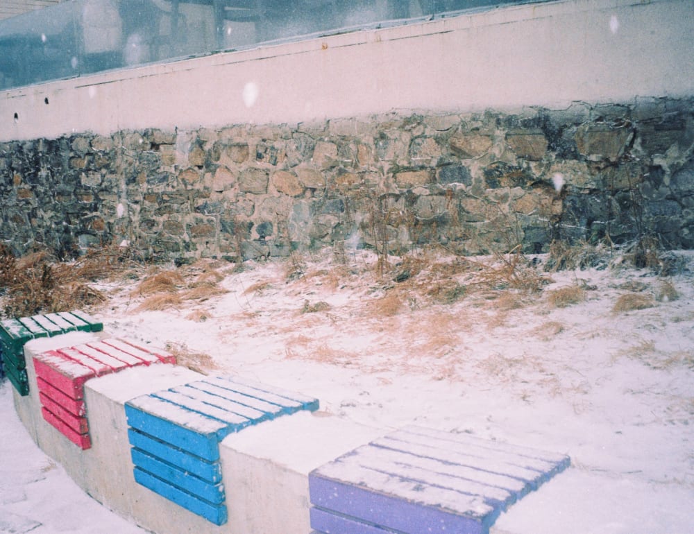 Colored benches beside a snowy stone wall