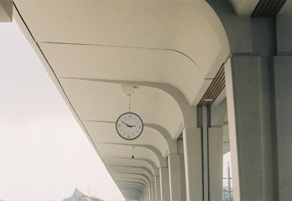 A clock beneath the arches of a railway platform