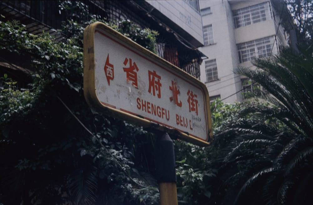 A street sign among trees and apartment buildings
