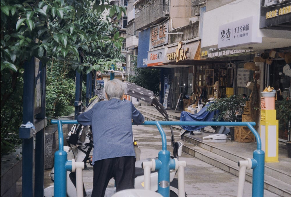 A person leaning on blue outdoor exercise equipment