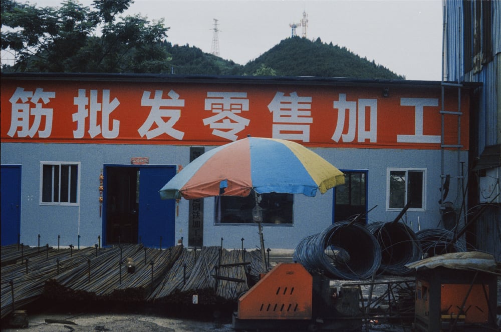 A colorful umbrella outside a steel workshop