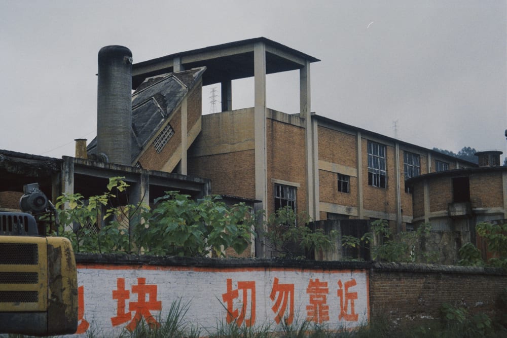 An old industrial building and chimney behind a wall